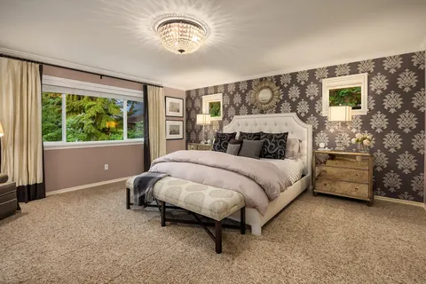 Primary bedroom with patterned accent wall and chandelier