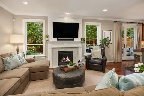 Family room with gas fireplace, white mantel, and garden views