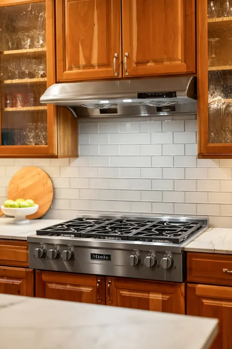 Professional gas range with subway tile backsplash and glass-front cabinets