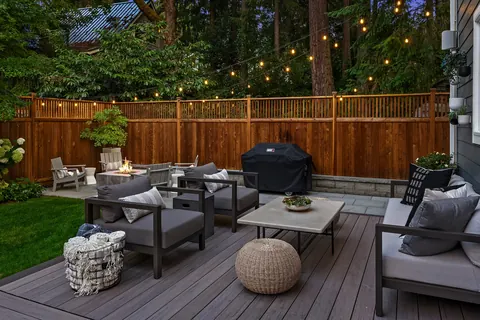 Deck lounge seating and grill beneath string lighting