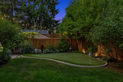 Putting green edged by hydrangeas and mature plantings