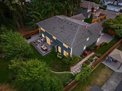 Aerial view over the home showing the fenced backyard, deck, and gardens